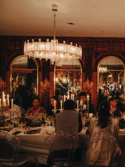 Guests dining in a room transformed to evoke the Hall of Mirrors, with arched mirrors and a grand chandelier. This image shows the complete ambiance we created for the Versailles-inspired event.
