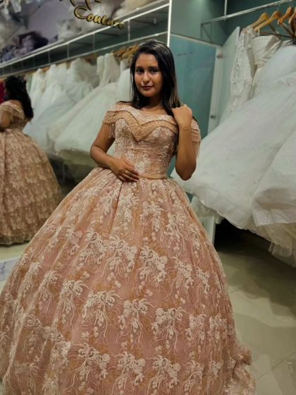 This dusty rose ball gown is pure romance. The entire dress is covered in delicate, ivory-toned lace embroidery, creating a beautiful texture. The off-shoulder neckline adds a soft, elegant touch.