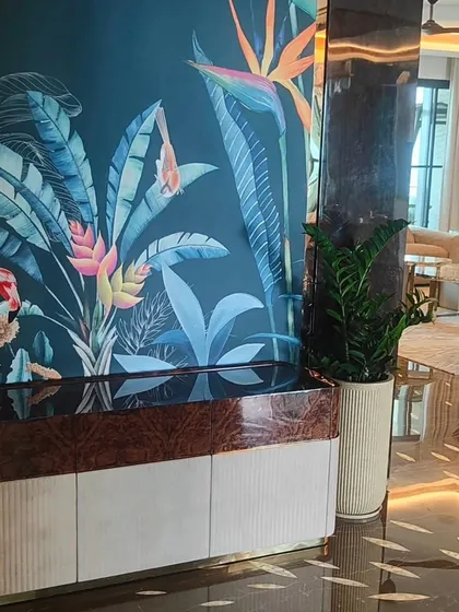 Indoor plantscaping is about finding the right plant for the right space. Here, a tall ZZ plant in a textured pot complements the room's luxurious decor and tropical-themed wallpaper, bringing a touch of green without overwhelming the design.