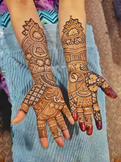 A beautiful blend of checkered patterns and cut-work in a traditional Indian style. The design is dense and detailed, covering the hands with a variety of classic mehndi elements.