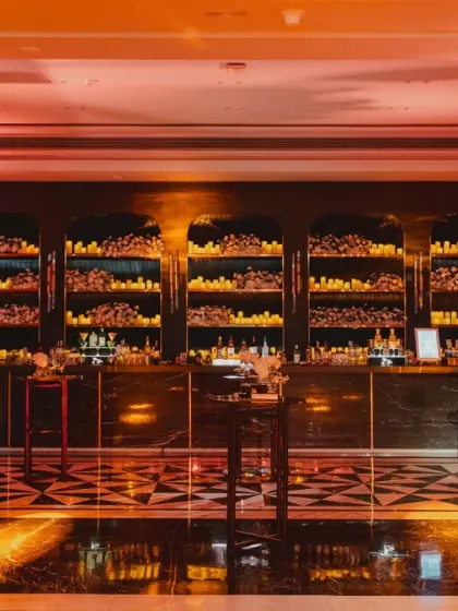 Lighting is our secret sauce for crafting the perfect vibe. This glamorous bar for a 'City of Dreams' theme uses moody lighting and a wall of candles to create an atmosphere of old-school elegance and high energy.