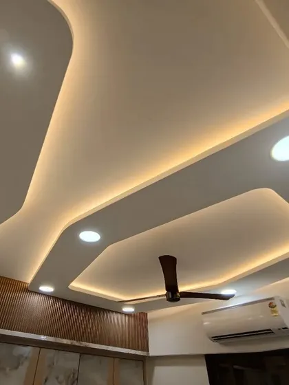 The finished look of a modern false ceiling design. The clean lines and multi-level structure, combined with warm lighting, add depth and sophistication to the room.