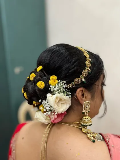 Floral buns are always a 10. This classic bun is decorated with a mix of yellow and white flowers, along with a traditional hair accessory, perfect for a South Indian bridal look.