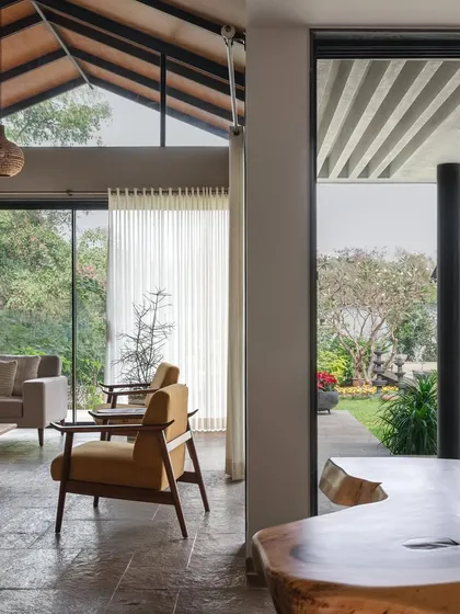 This view from the dining area into the living room at Grove House highlights the seamless indoor-outdoor connection. The entire space opens up to the garden, embodying the spirit of a tropical weekend retreat.