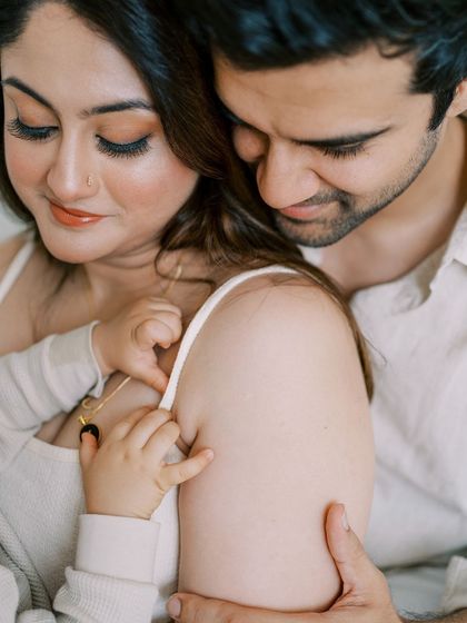 A close-up of a couple cuddling with their baby. The focus on their hands and faces creates a very intimate and emotional portrait.