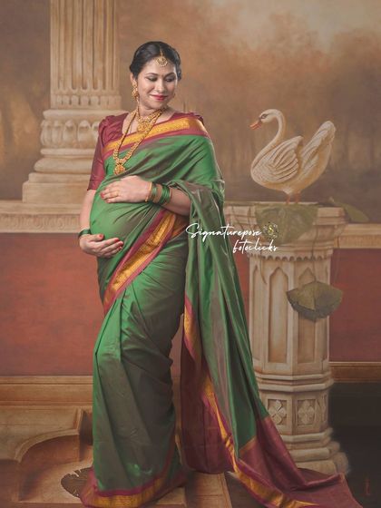 A serene portrait in a green saree, capturing a moment of quiet contemplation against a painted backdrop.