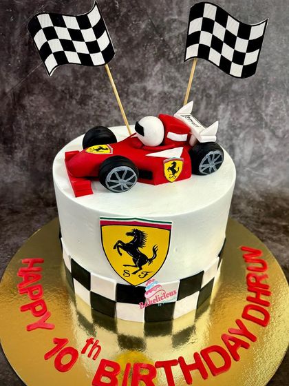 A sleek Ferrari-themed cake for a 10th birthday celebration. It features the iconic red race car, checkered flags, and the Ferrari logo, all completely edible.