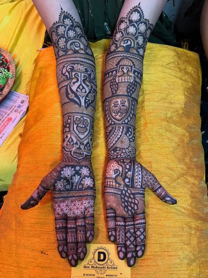Both hands adorned with symmetrical bridal mehndi. This design features peacocks, paisleys, and detailed finger work, creating a balanced and elegant look.