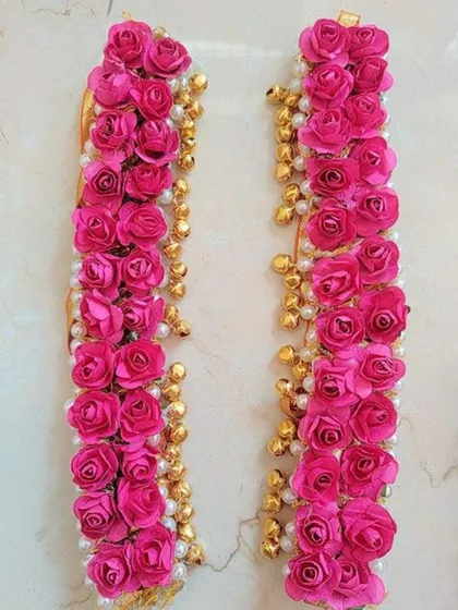 A detailed view of floral kalire or bracelets, made with pink roses and golden bells, a perfect accessory for a bride's Haldi or Mehendi.