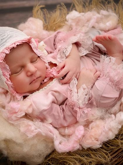 A close-up of the vintage storybook setup, focusing on the baby's peaceful expression while wearing a delicate lace bonnet and pink ruffled outfit.