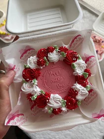 A close-up of a Mother's Day bento cake with a beautiful wreath of red and white piped roses.