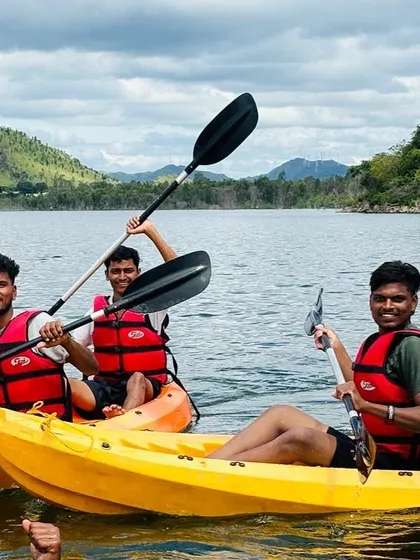 Three friends share a laugh while kayaking at Vani Vilas Sagar, showcasing the social and fun side of our camps.