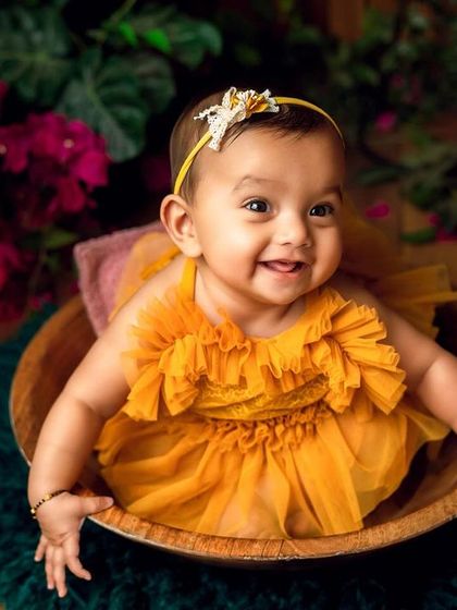 Sitting pretty in a wooden bowl, this little one shines in her bright yellow dress against the floral backdrop.