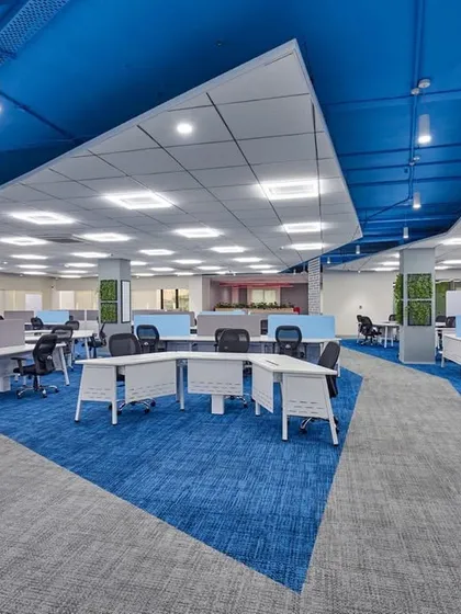 A large, agile workspace with a dynamic blue and grey carpet pattern. The ceiling is painted a deep blue, and green walls are used as accents, creating a vibrant and engaging environment.