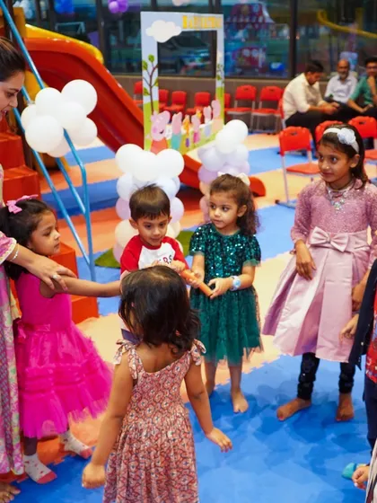 Kids playing a game of "Ring a Ring o' Roses" on the play mat, a simple and joyful moment.