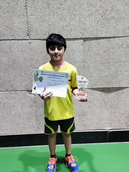 A proud Arth Dubey holding his runner-up trophy and certificate from the Ramsheth Thakur Badminton Trophy tournament.