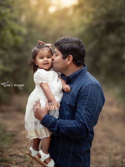 A father's gentle kiss for his daughter. The soft, diffused light of the outdoor setting creates a tender and heartwarming portrait of their special bond.