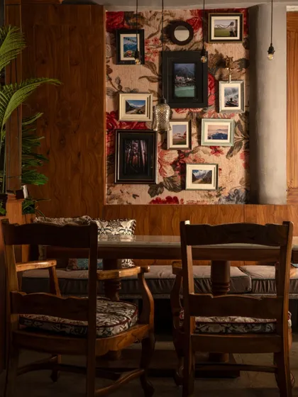 A closer view of the dining nook, highlighting the mix of textures and patterns. The cushioned seats and dark wood chairs provide comfort, while the curated art adds a personal, collected touch.