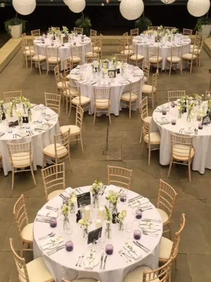 An elegant terrace decoration for a home wedding. We used round tables with white linens, classic Chiavari chairs, and hanging paper lanterns to transform the space into a beautiful celebration venue.