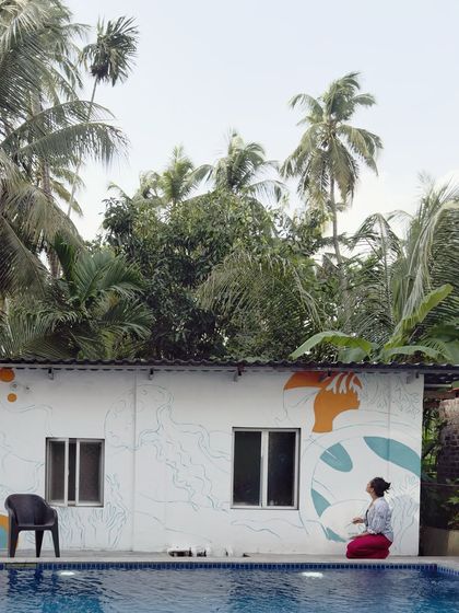 A wider view showing the scale of the poolside wall project. Set against a backdrop of coconut trees, this mural was designed to complement the natural beauty of the Alibaug resort.