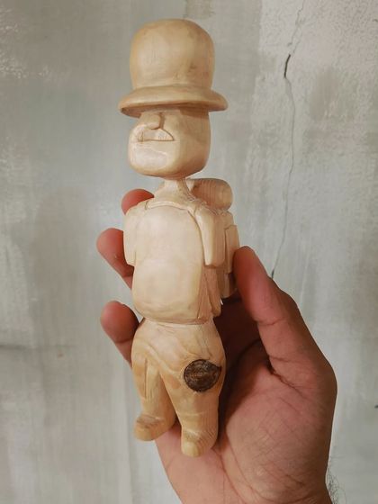 A duplicate of 130, a front view of our little wooden traveler. You can see the details of his mustache and backpack, all hand-carved with care.