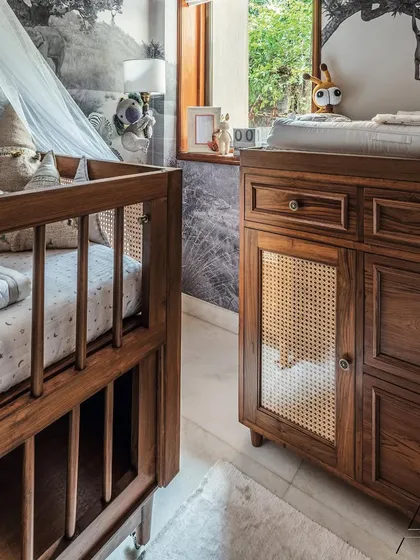The details in this nursery are all about texture. I paired a classic wooden crib with a matching changing table that has woven cane door panels, adding a touch of timeless craftsmanship.