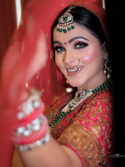 A beautiful smiling portrait of the bride, her face framed by her red dupatta.