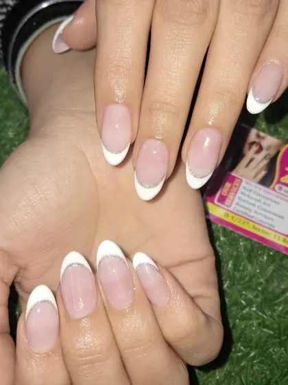 A close-up showing the clean lines of our classic French manicure with a delicate silver glitter accent.