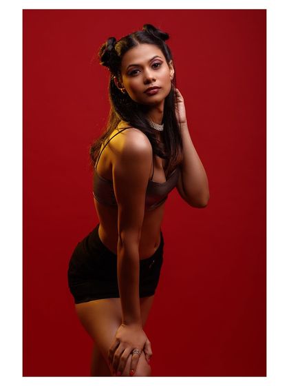 A simple yet powerful pose that showcases the outfit against the striking red backdrop.