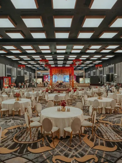 A wide-angle view of the ballroom, showcasing the grand scale of the wedding reception setup. The elegant guest seating is arranged to offer a perfect view of the central mandap, ensuring everyone feels part of the celebration.