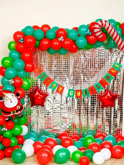I created this classic Christmas photo booth with a shimmering silver foil curtain and a red and green balloon frame. It includes fun elements like a candy cane balloon and a 'Merry Christmas' banner for memorable party pictures.