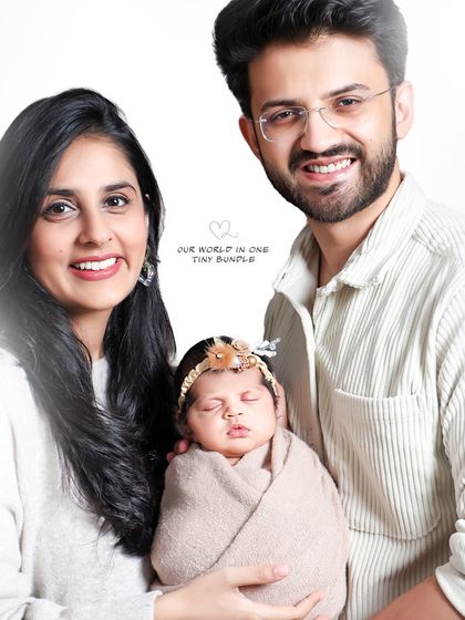 A classic family portrait against a clean, bright background. The parents' proud smiles and the baby's peaceful sleep come together to create a perfect memory of this special time.