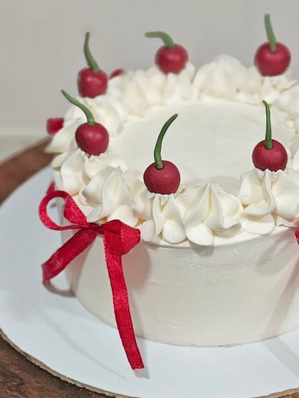 A close-up on the cute, handcrafted fondant cherries sitting on top of the fluffy buttercream swirls.