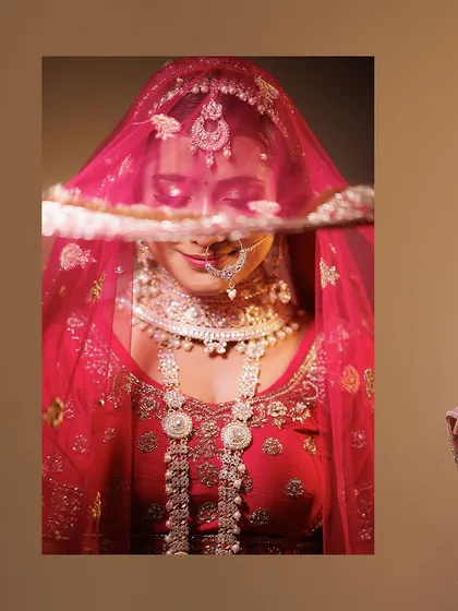 A classic bridal portrait focusing on the intricate details of the bride's attire. The delicate veil, the traditional jewelry, and her serene expression are captured with soft, artistic lighting to create a timeless image.