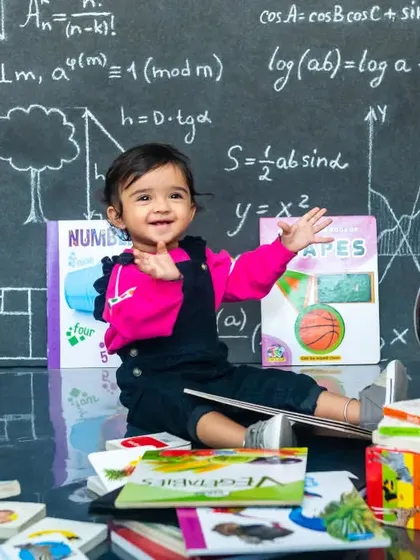 A fun, Einstein-themed photoshoot featuring a baby sitting in front of a chalkboard full of equations, surrounded by books and a globe.