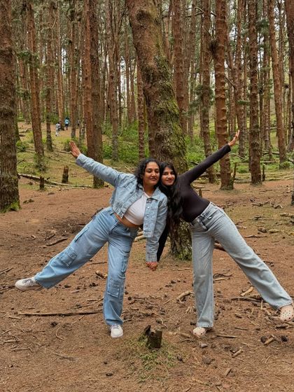Two friends striking a pose in the middle of the woods, enjoying the freedom of nature.