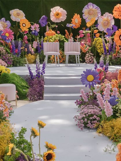 The central aisle and stage for the 'A Blooming Day' ceremony, creating a fantastical pathway for the couple through a field of colorful, oversized flowers.