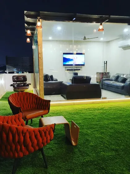 A view from the lawn towards the glass room at night. The comfortable accent chairs provide a perfect spot to enjoy the ambiance.