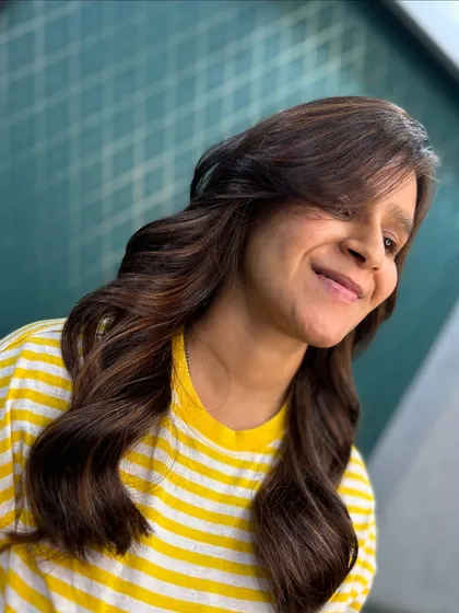 The client is all smiles with her new hair. The side-swept fringe and soft waves give this colour a playful and happy vibe.