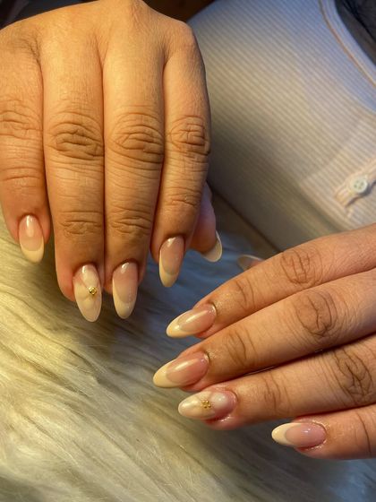 A beautiful and subtle summer nail design. This look features a soft, natural ombre with a delicate, hand-painted white flower and a single gold stud for a touch of minimalist elegance.