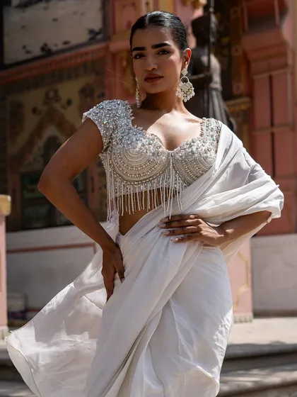 A stunning piece from our Ivory Edit. This pure white saree is paired with a breathtaking, fully beaded blouse with hanging pearl tassels.