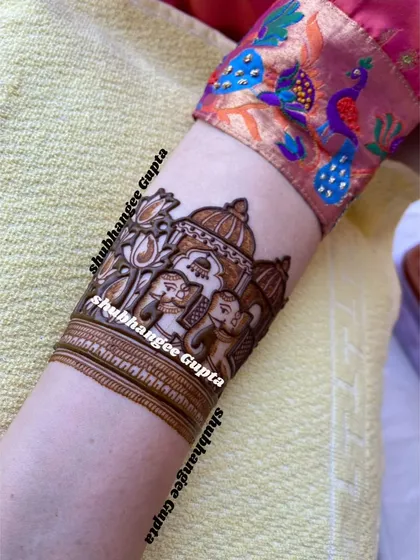 A close up of an elephant motif on an armband. This design shows a royal elephant with a decorative covering, set against a backdrop of a palace structure.