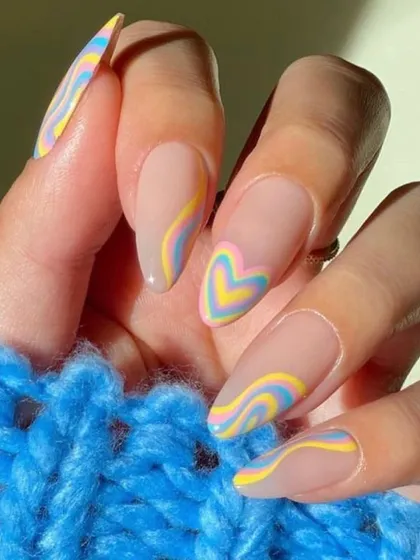 Pastel dreams come to life with this almond-shaped manicure. It features a mix of soft swirls and a central heart design in pastel yellow, blue, and pink for a soft, whimsical look.
