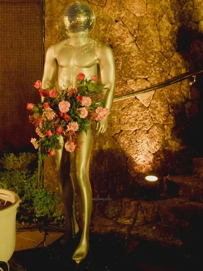 A silver mannequin with a disco ball head, holding a bouquet of pink flowers. This avant-garde decor piece was a playful and glamorous addition to the sangeet.