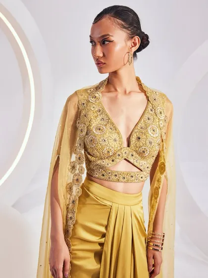 The Lydia Cape Set, crafted from fine weaves and luxurious textiles. The ensemble features a breezy, embellished cape, a detailed blouse, and a pre-draped solid skirt.