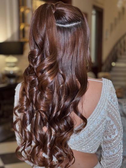 A chic half-ponytail with a clean parting and voluminous curls.