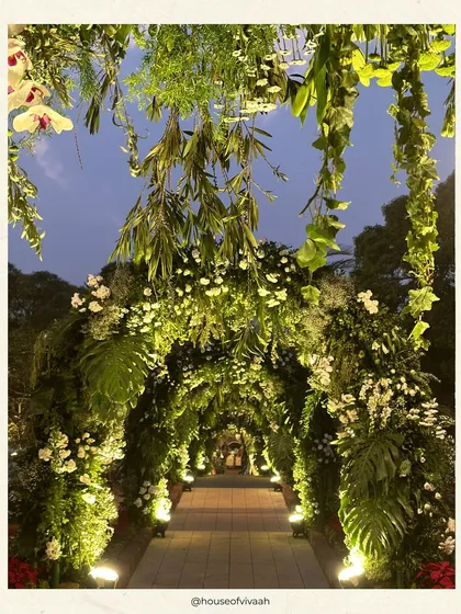 An ethereal floral archway creates a magical entrance path for a wedding in the hills of Mahabaleshwar. The design uses lush foliage and white blooms to craft an immersive, nature-inspired experience.