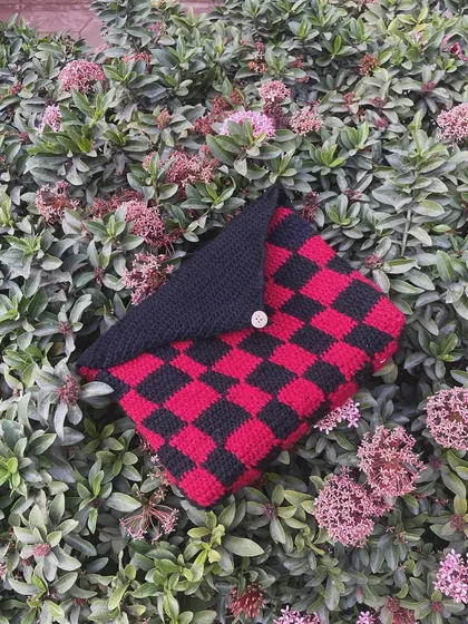 My checkerboard book sleeve in red and black. It has a flap and a button to make sure your book stays protected.
