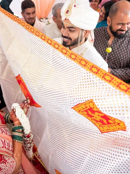 A key moment in a Gujarati wedding, the 'Antarpat' cloth is lowered, and the couple sees each other for the first time at the mandap.