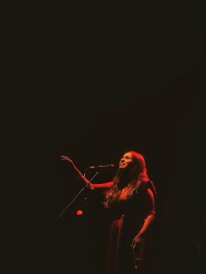 A single red light illuminates the stage during the 'Vari' album release concert. The mood and lighting are so important for setting the emotional tone of the music.